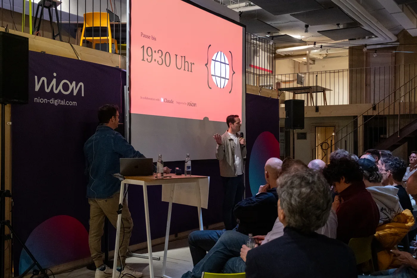 Bühne mit Pausenfolie und Publikum beim ersten Claude Code Meetup