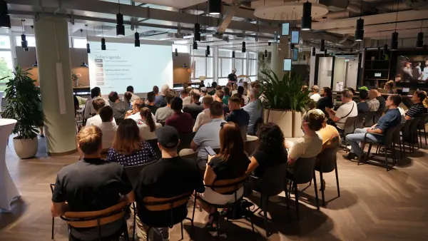 Voller Saal beim Auftakt von Meetup #7 – Teilnehmende vor der Agenda-Leinwand bei 1000 Satellites