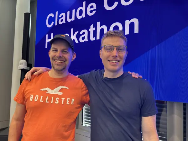 Florian Steiner und Michael Whelehan vor der Leinwand „Claude Code Hackathon“ im IT-Rathaus