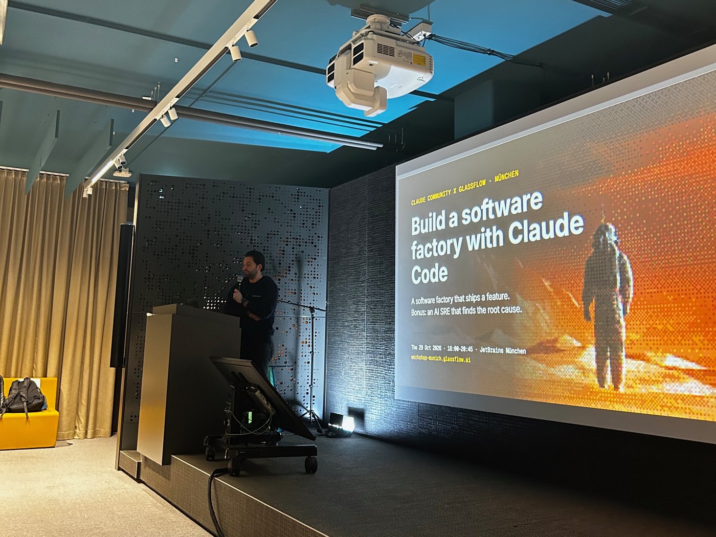 Bühne bei JetBrains München mit der Titelfolie „Build a software factory with Claude Code“ und dem Speaker am Pult.
